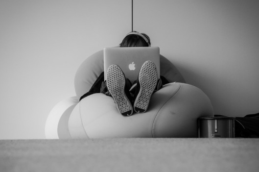 Man sitting alone with computer covering his face
