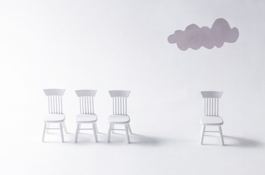 one chair separated from group of chairs with grey cloud over it