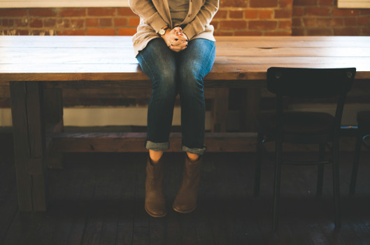 Woman sitting on table clasping her hands | On Being Introverted and Asian