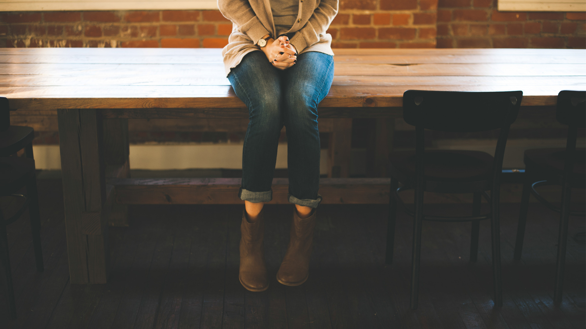 Woman sitting on table clasping her hands | On Being Introverted and Asian