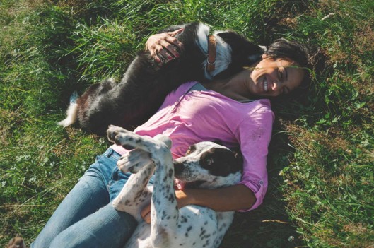 Woman Playing with Dogs in Grass | What We're Reading: The Importance of Play