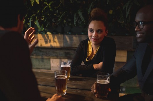 Three professionals around a table discussing something over drinks -- 4 Low-Risk Strategies for Expanding Your Network