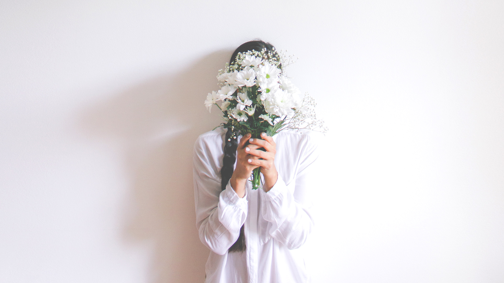 woman hiding behind bouquet of flowers