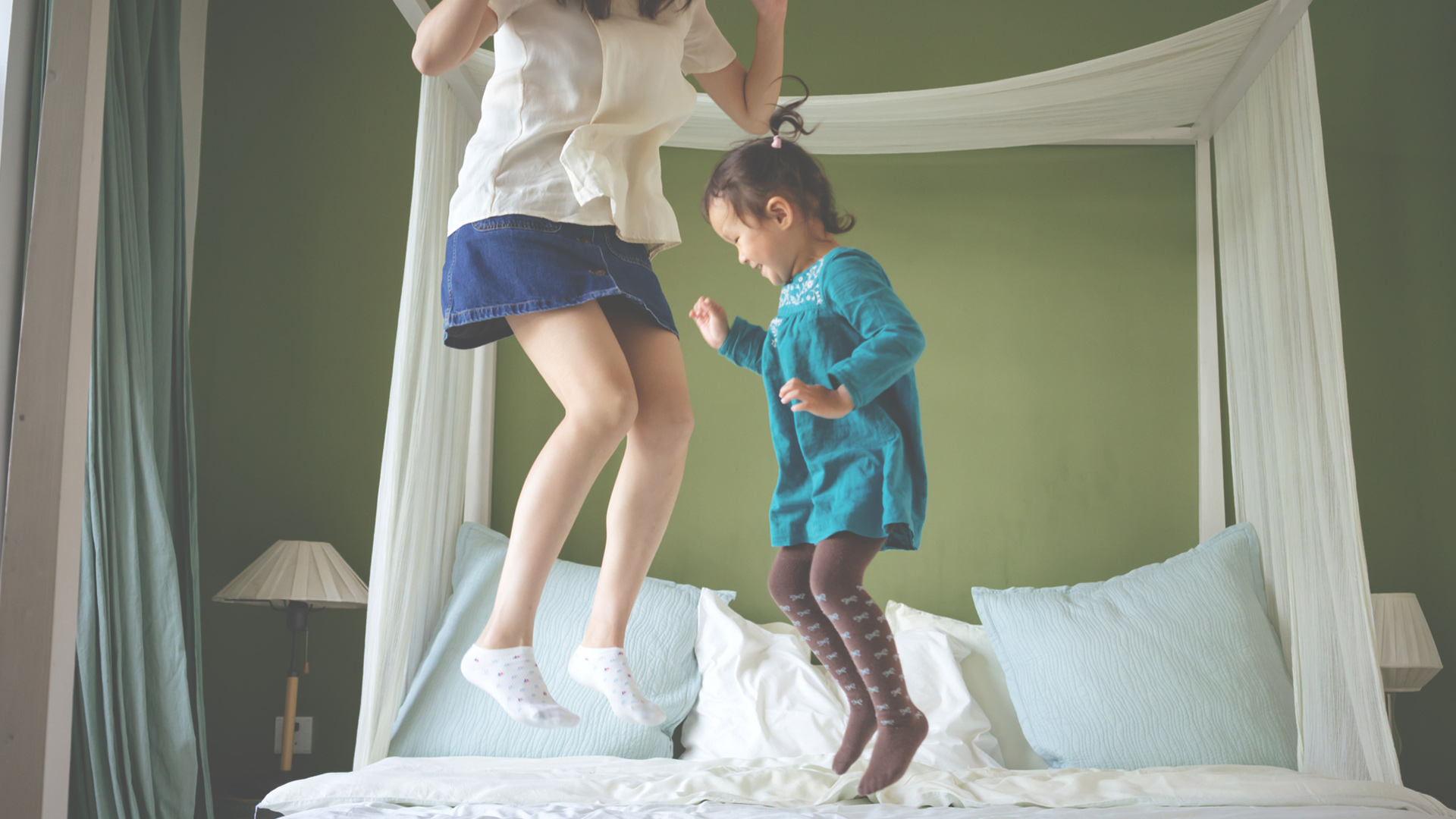 Mother and daughter jumping on the bed