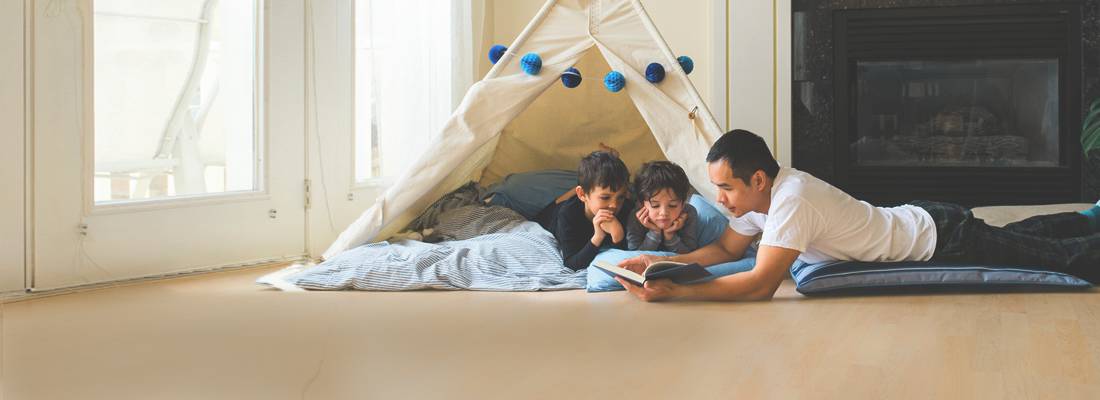 Father reading to kids in tent in house during daytime