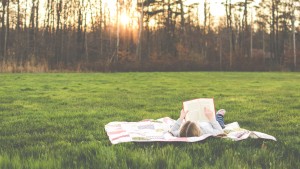 Girl reading book alone on the grass