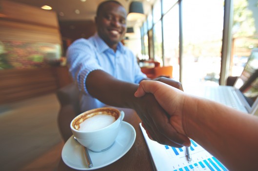 Man shaking hand while drinking coffee