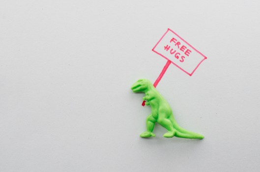 toy t-rex with free hugs sign