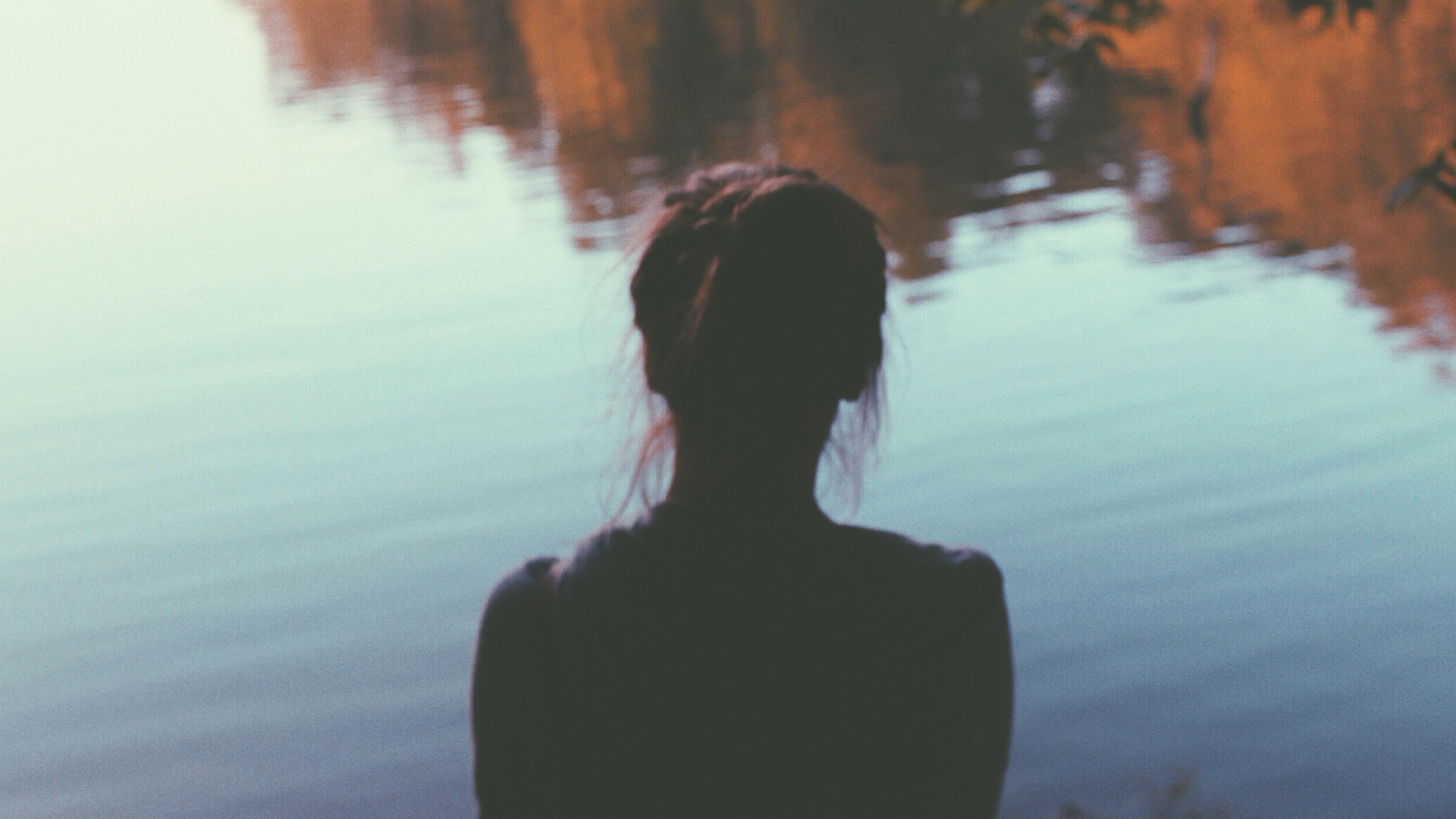 woman sitting looking at a lake