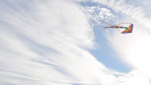 Kite flying through a sunny but cloudy sky